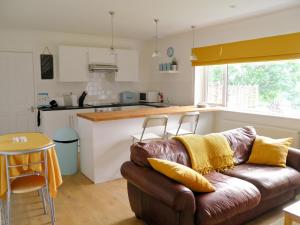 Una sala de estar con un sofá y una cocina. en Weavers Lodge, en Ibsley