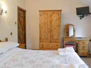 een slaapkamer met een bed met een ladekast en een spiegel bij The Granary in Colyford