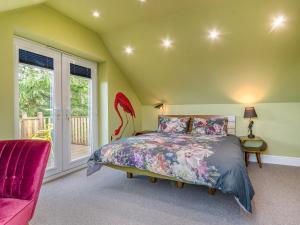 a bedroom with a bed and a chair and a window at The Aviary-Uk44382 in Callington