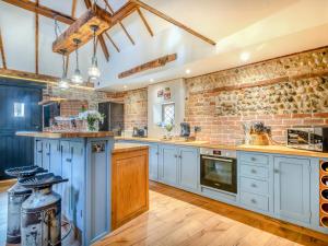 a large kitchen with white cabinets and a brick wall at Bockety Barn in Stalham