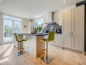 a kitchen with a counter and two green chairs at Old Barn 1 - Uk48477 in Ferndown +18 photos