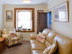 ein Wohnzimmer mit einem Ledersofa und einem Stuhl in der Unterkunft Boatmans Cottage - 27787 in Portessie