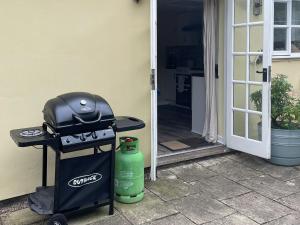 un gril et un récipient vert à côté d'une porte dans l'établissement Orchard Bank Cottage, à Longhope