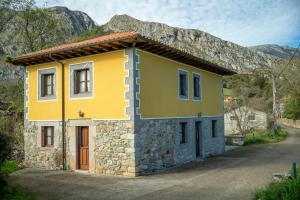 ein gelbes Haus mit einem Berg im Hintergrund in der Unterkunft Casa Collado Santo Tomás in Bodes