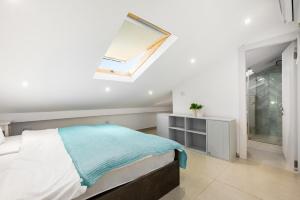 a white bedroom with a bed and a skylight at Sunny Hilltop Hideaway by Sea N' Rent in Tefahot