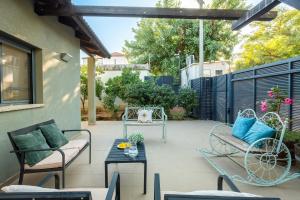 a patio with chairs and tables and a fence at Sunny Hilltop Hideaway by Sea N' Rent in Tefahot