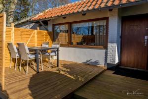 a wooden deck with a table and chairs on a house at FeWo Lille Lægehus in Hjørring