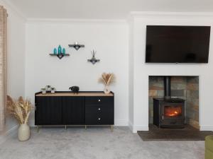 een woonkamer met een open haard en een tv aan de muur bij Sealladh Na Mara in Pollachar