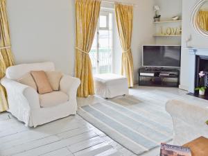 a living room with a white chair and a television at Waters Edge in Instow