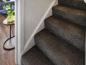 a stairway with a vase of flowers on a table at Salty Paws in Gorleston-on-Sea