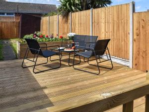 a patio with chairs and a table on a wooden deck at Salty Paws in Gorleston-on-Sea