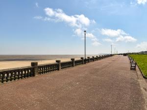 a beach with a fence and a sidewalk and the ocean at Salty Paws in Gorleston-on-Sea +6 photos