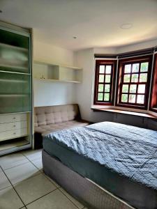 Schlafzimmer mit einem Bett, einer Kommode und einem Fenster in der Unterkunft Apartamento duplex em Praia do Forte - 2 suítes in Praia do Forte