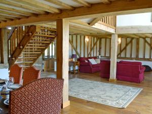 a living room with red chairs and a staircase at Romden Barn in Smarden