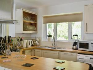 a kitchen with white cabinets and a wooden counter top at Mill Haven in Dunster