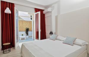 Schlafzimmer mit einem weißen Bett und roten Vorhängen in der Unterkunft Fuorlovado 40 in Capri