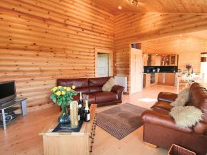 a living room with leather furniture in a log cabin at Bracken Log Cabin - S4468 in Glenfarg