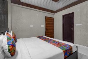 a bedroom with a bed in a room with a door at FabHotel Vrishti Residency in Greater Noida
