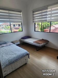 a bedroom with two beds and two windows at B&C Homestay in Miri