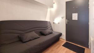 a black bed in a room next to a door at Studio tout équipé, piscine chauffée, départ skis aux pieds in Les Orres
