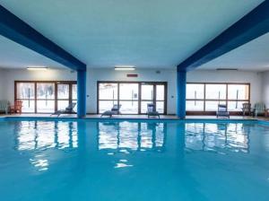 a large swimming pool with blue walls and windows at Studio tout équipé, piscine chauffée, départ skis aux pieds in Les Orres