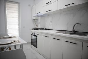 a white kitchen with a sink and a stove at Garsonieră Studio in Dudu