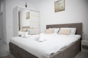 a large white bed in a white room with a mirror at Garsonieră Studio Militari Residence in Dudu