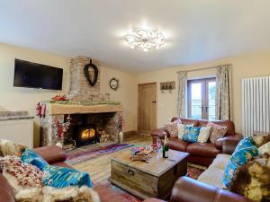 a living room with leather furniture and a fireplace at Farriers Lodge in Burshill