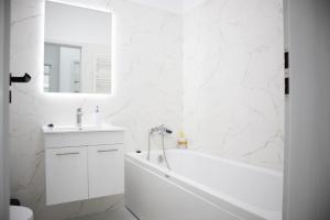 a white bathroom with a tub and a sink at Garsonieră Studio in Dudu +9 photos