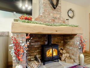 a brick fireplace with a wood burning stove at Farriers Lodge in Burshill