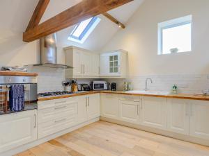 a kitchen with white cabinets and a stove top oven at Westwood Barn in Brough Sowerby +15 photos