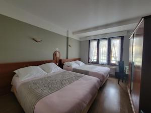 two beds in a room with two windows at Touring Hotel in Bellegarde-sur-Valserine