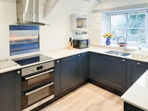 a kitchen with black cabinets and a sink at Appleloft in Crackington Haven +25 photos