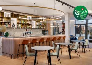 比尔Courtyard by Marriott Biel Bienne的酒吧前设有桌椅的餐厅