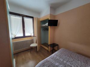 a small bedroom with a bed and a window at Touring Hotel in Bellegarde-sur-Valserine