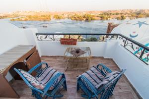 a balcony with two chairs and a table on a ship at Casa Nile View rooms - Nubian House in Aswan