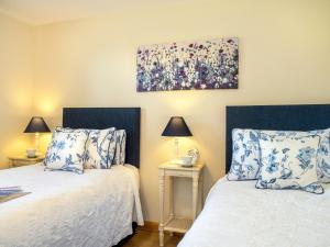 Blackberry Cottage في North Hill: غرفة نوم بها سريرين ولوحة على الحائط
