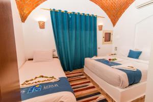 two beds in a room with a blue curtain at Casa Nile View rooms - Nubian House in Aswan