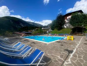 una piscina con sillas azules y gente en ella en Sporting Hotel Club, en Pelos