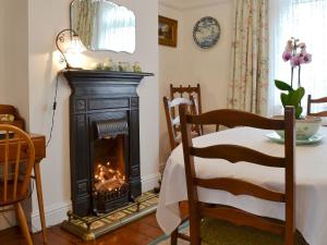 een open haard in een kamer met een tafel en een stoel bij Greenbank Cottage in Hilgay