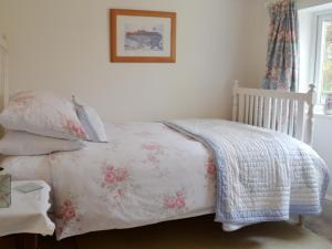 een slaapkamer met een bed met een deken en kussens bij Greenbank Cottage in Hilgay +19 foto's