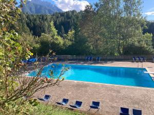 Una piscina con sillas y montañas al fondo. en Sporting Hotel Club, en Pelos
