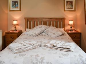 a bed with white blankets and two nightstands with lamps at Bramble Cottage-19878 in Cloughton