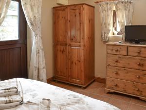 a bedroom with a bed and a wooden cabinet and a television at Bramble Cottage-19878 in Cloughton