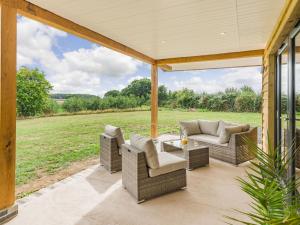 a patio with couches and a table and a field at Oak Tree Lodge - Uk38383 in Lyonshall