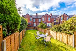 een achtertuin met een tafel en stoelen en een hek bij Charming family home in Heaton Norris