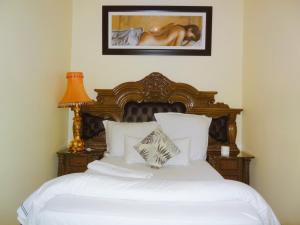 a bedroom with a bed with white sheets and a lamp at Pro Max Guesthouse Goodwood in Goodwood