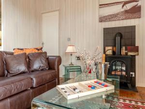 a living room with a leather couch and a fireplace at Beech Tree Lodge in Willington