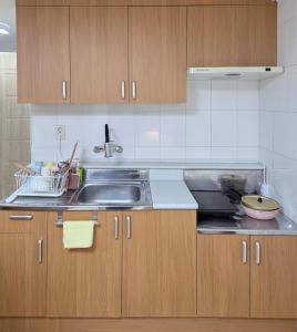 Una cocina con fregadero y armarios de madera. en Exit 4 of Hongik University, en Samgong-ni