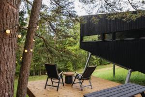 a deck with two chairs and a table and a tree at Blackview cabin in Kulautuva